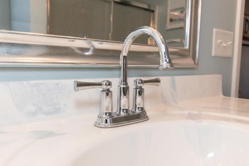 a bathroom sink with a faucet and a mirror at At the Beach - Old Homestead Beach House in Huron