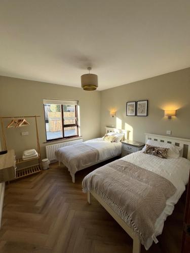 a bedroom with two beds and a window at Woodview Cottage in Mill Loughan