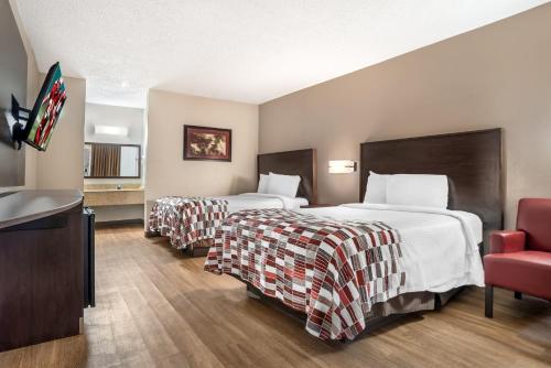 a hotel room with two beds and a red chair at Red Roof Inn Montgomery - Midtown in Montgomery