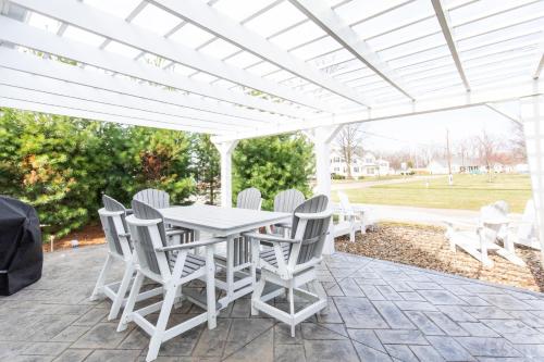 a white table and chairs under a white pergola at At the Beach - Old Homestead Beach House in Huron