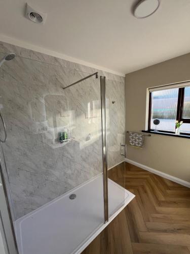 a bathroom with a shower with a glass door at Woodview Cottage in Mill Loughan
