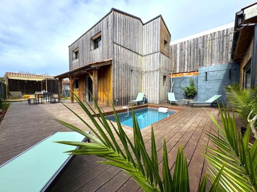 - un bâtiment en bois avec une piscine en face dans l'établissement Havre du Bassin avec piscine et studio indépendant, à Gujan-Mestras