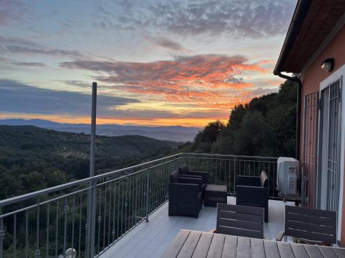 a balcony with chairs and a sunset in the mountains at "Casa Parletto" - Villa Esclusiva con Piscina in Caldana