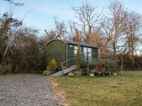 a green tiny house sitting on top of a field at Perch Hut in Uckfield