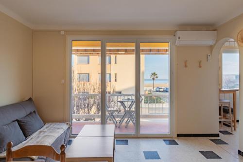 Una sala de estar con un sofá y un balcón. en Les Jacinthes - Spacious sea view, en Port-la-Nouvelle