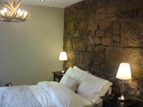 a bedroom with a stone wall and a bed with pillows at Riggend Farm Bed and Breakfast in Airdrie