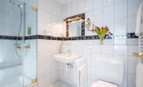 a bathroom with a sink and a toilet and a mirror at Residenz Seeterrasse Restaurant & Hotel in Wangen