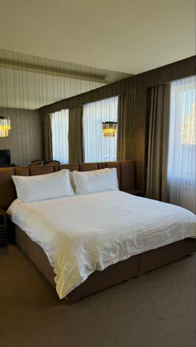 a bedroom with a large bed with white sheets and pillows at Barhat Hotel & SPA in Taraz