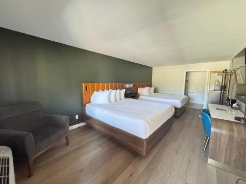 a hotel room with two beds and a chair at SureStay by Best Western Morgan Hill in Morgan Hill