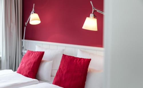 two red pillows on a white bed with red wall at Residenz Seeterrasse Restaurant & Hotel in Wangen