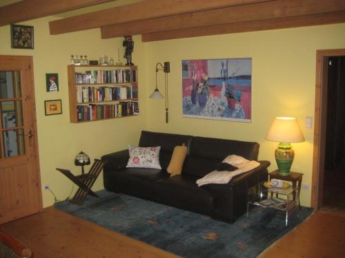ein Wohnzimmer mit einer schwarzen Couch und einem Bücherregal in der Unterkunft Ferienhaus bei Berlin in Falkensee
