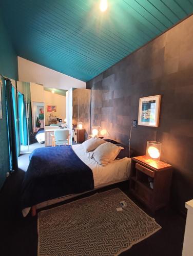 une chambre avec un lit et une table avec une lampe dans l'établissement L'Esprit Vintage, à Mérignac