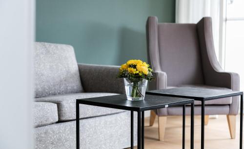 a vase of yellow flowers on a table next to a chair at Residenz Seeterrasse Restaurant & Hotel in Wangen