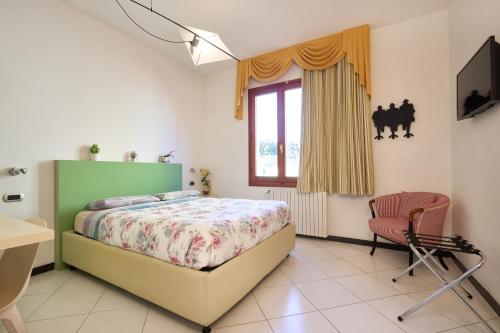a bedroom with a bed and a chair and a window at Il Fiore di Monnalisa in Vinci
