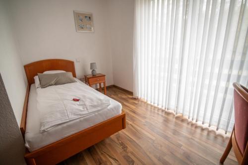 a small bedroom with a bed and a large window at Waldhotel Schipp-Hummert in Emsdetten