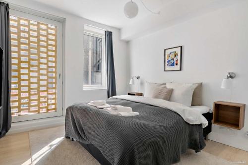 a white bedroom with a large bed and a window at Superb First-Floor Mid Town Apartment in Aarhus