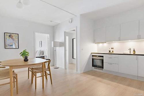 a white kitchen with a table and a dining room at Superb First-Floor Mid Town Apartment in Aarhus