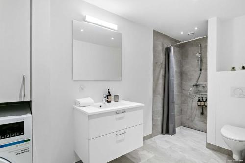 a white bathroom with a sink and a shower at Superb First-Floor Mid Town Apartment in Aarhus