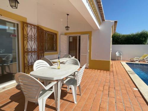 a patio with a table and chairs and a pool at Villa Ana in Albufeira