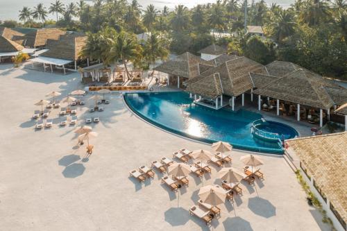 an aerial view of a resort with a pool and chairs at Cinnamon Hakuraa Huraa Maldives - All Inclusive in Meemu Atoll