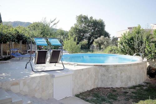 a swimming pool with two chairs next to it at Villa Rezevici in Katun