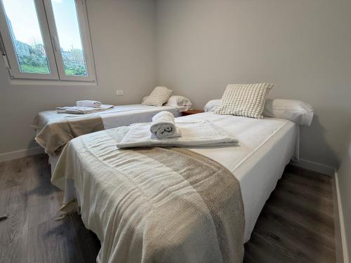 two beds with towels on them in a room at Oktheway Corme in Corme-Puerto