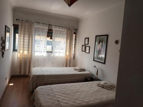 ein Schlafzimmer mit zwei Betten und einem Fenster in der Unterkunft Terraço da Baía in São Martinho do Porto