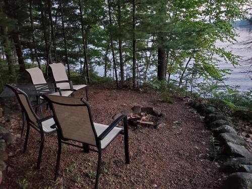 a group of chairs sitting around a fire next to the water at Boulder Lakehouse in Boulder Junction