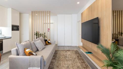 a living room with a couch and a flat screen tv at Bright 2BR Flat near Praça da Galiza by LovelyStay in Porto