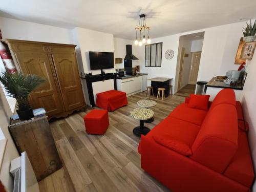 a living room with a red couch and a kitchen at Serre Chevalier 2 pièces au cœur du centre historique in Briançon