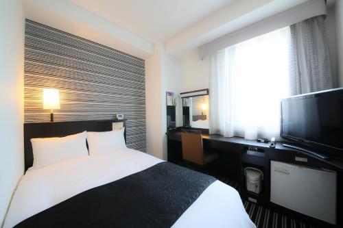 a hotel room with a bed and a flat screen tv at APA Hotel Kagoshima Tenmonkan in Kagoshima