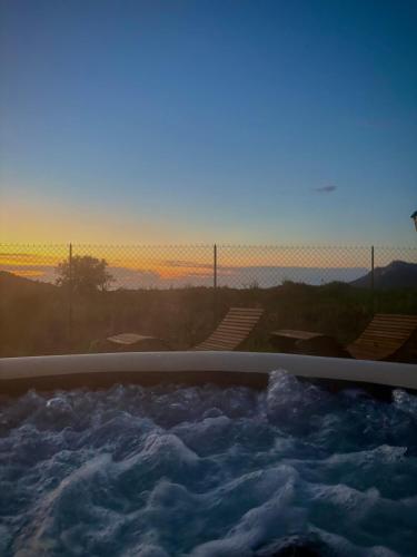 une baignoire jacuzzi remplie d'eau avec le coucher du soleil dans l'établissement T3 Baie de Calvi jardin panoramique vue mer, à Calenzana