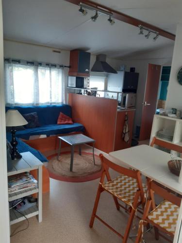 un salon avec un canapé bleu et une table dans l'établissement Joli mobilhome, à La Baule