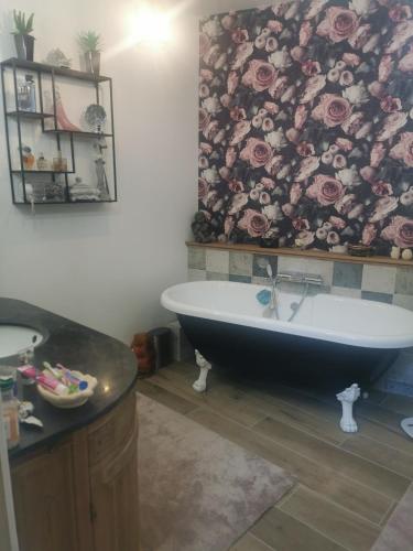 La salle de bains est pourvue d'une baignoire et d'un mur fleuri. dans l'établissement Maison tout confort entre terre et mer en Normandie, à Douvres-la-Délivrande
