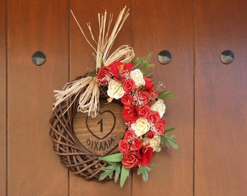 a wreath on a door with a sign on it at Oihalia Guesthouse in Fidhákia
