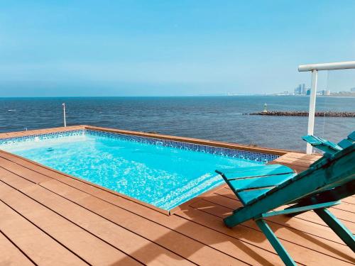 a chair and a swimming pool on a deck with the ocean at FRENTE PLAYA vista al mar, PISCINA DE USO EXCLUSIVO in Boca del Río