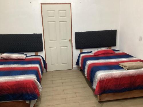 a room with two beds and a white door at Vuelo del Águila 4 suites 6 bathrooms alberca in La Esperanza