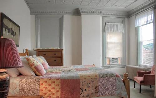a bedroom with a bed and a dresser and two windows at Shamokin Bed and Breakfast in Shamokin
