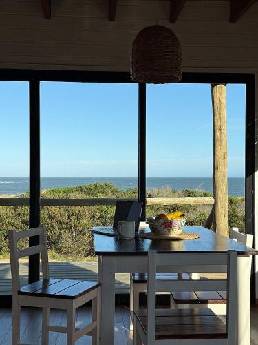 a table with a bowl of fruit and a laptop on it at Casa frente al mar Papaya Grande in Punta Del Diablo