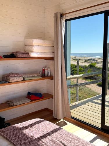 a bedroom with a bed and a window with a view at Casa frente al mar Papaya Grande in Punta Del Diablo