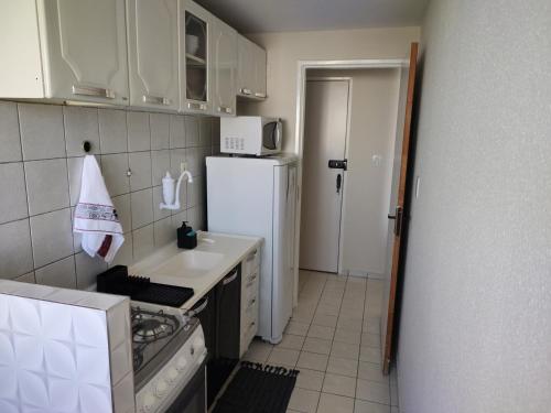a small kitchen with a refrigerator and a sink at Apto próx ao Shopping e Centro Petrolina PE in Petrolina
