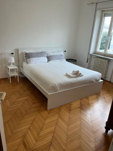 a white bed in a room with a wooden floor at Ca Re Dante in Pordenone