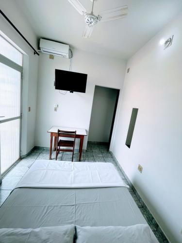 een kamer met een tafel, een stoel en een tv bij Hotel Hebron in Três Marias