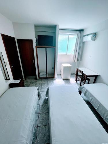 een kamer met twee bedden, een tafel en een bureau bij Hotel Hebron in Três Marias