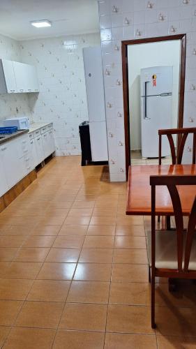 an empty kitchen with a table and a refrigerator at Casa Completa até 20 pessoas in Ribeirão Preto
