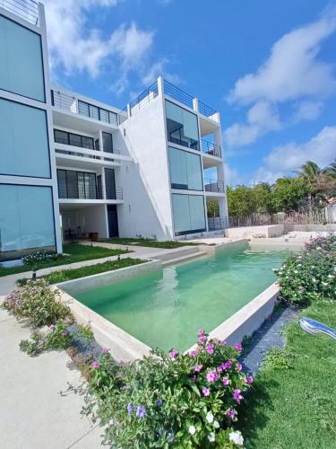 a building with a swimming pool in front of a building at Oceanfront 2Bed - 2Bath Paradise Mahahual in Mahahual