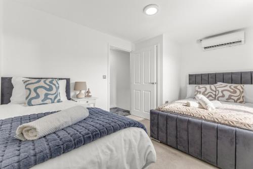 two beds in a bedroom with white walls at Large Family House with free parking - 3 bedrooms 6 beds in Manchester