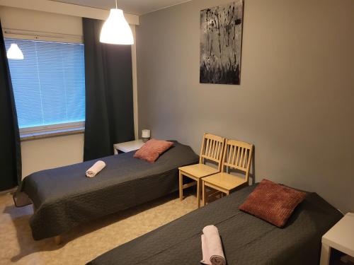 a bedroom with two beds and a chair and a window at Center apartment Joensuu in Joensuu