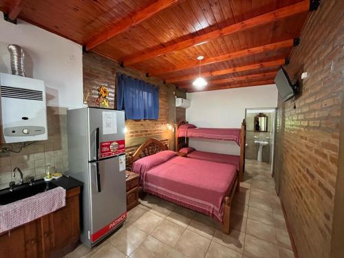 a small kitchen with two beds and a refrigerator at Departamentos La Morita in Embalse
