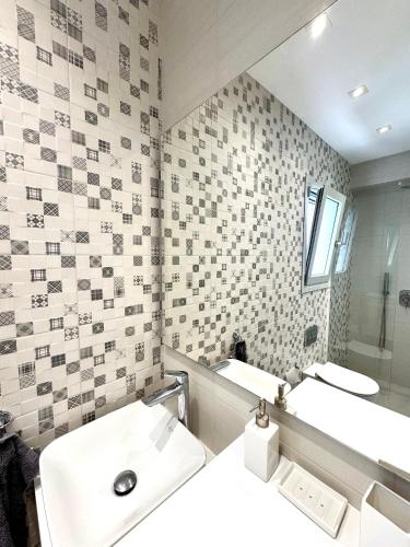 a bathroom with a white sink and a mirror at Anemoni Beach Hotel in Skiathos Town